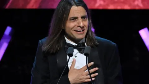 Getty Images A man looks emotional as he stands at a podium