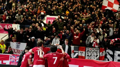 PA Media Bristol City players celebrate a goal against Middlesbrough while in the background hundreds of fans celebrate in the stands