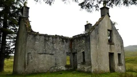 BBC/Uncanny The lodge is just a shell. The roof, doors and windows are gone. A wall and the gable ends are still standing.