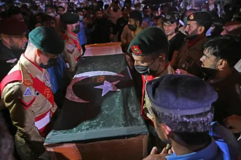 AFP via Getty Images Soldiers prepare to place the flag-draped coffin of nuclear scientist Abdul Qadeer Khan during his funeral