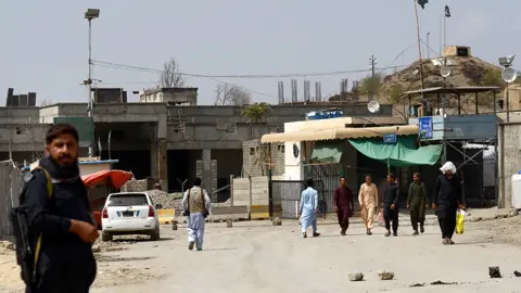 Getty Images People wait by the key border crossing as trucks carrying goods destined for Afghanistan line up, following clashes between security forces of Pakistan and Afghanistan, in Torkham, Pakistan on September 07, 2023