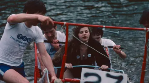 Knaresborough Lions Club (Steve Sowerby) A lady clings onto a red metal framed bed being pushed by her teammates through the river