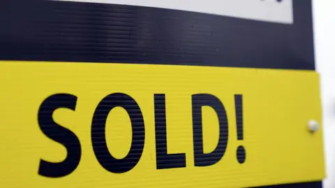 Steve Parsons/PA Wire An estate agent's board, with the word 'sold!' in blue capital letters on a yellow background.
