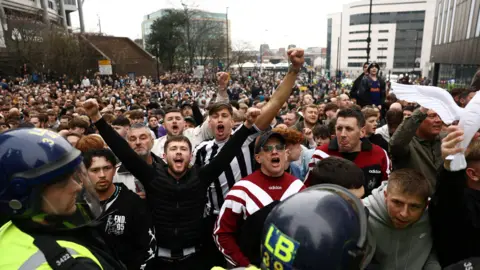 A sea of Newcastle fans outside St James's are being held back by police officers in riot gear, to keep them separated from Sunderland fans. 