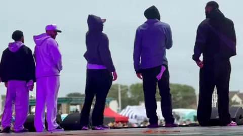 Five member of Diversity, seen from the back of the stage. The photo is from floor level and they are looking out over the crowd.