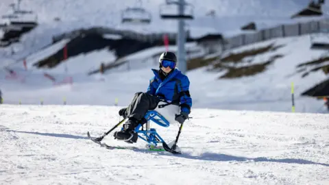 Cameron Ross Hall/Holmlands Josh skiing in the mountains on a disability ski chair