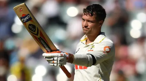 Australia wicketkeeper Alex Carey raises his bat after hitting a century