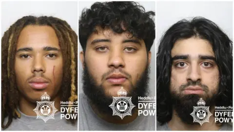 Komposit Polisi Dyfed-Powys dari gambar Mugshot Polisi Elijah Ogunnubi-Sime yang memiliki kepang rambut gimbal dan jenggot tipis, Mohammad Comrie yang memiliki rambut hitam bergelombang pendek dan jenggot hitam panjang dan faiz shah memiliki rambut hitam panjang dan beruang dagu hitam panjang. Mereka mengenakan kaus abu -abu