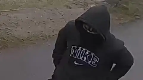 Person wearing a black hoodie and mask.