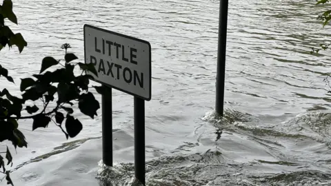 Harriet Heywood/BBC A Little Paxton road sign sticking out of the flood water. 