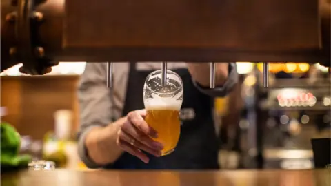 Getty Images/miodrag ignjatovic Unrecognizable man pouring a beer on beer tap in drinking glass, in a pub