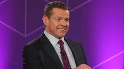 Rhun ap Iorwerth smiling at the audience watching him answer questions