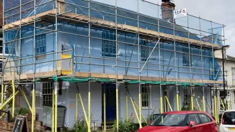 Luke Deal/BBC The outside of The Red Lion - a white building with scaffolding around it