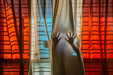 Pubarun Basu Shadows of railings and silhouettes of hands behind curtains