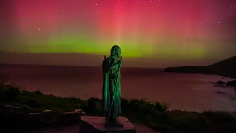 Martin Davies Northern lights behind St Crannog's Statue in Llangrannog, Ceredigion