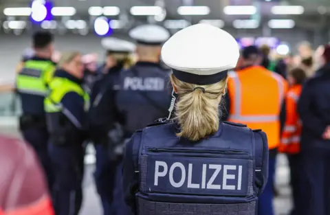 A woman in police uniform pictured with other police and security staff in background