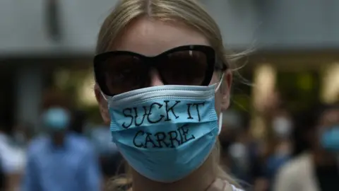 AFP A pro-democracy demonstrator wears a mask that reads "suck it Carrie" as she and others gather at Chater Garden