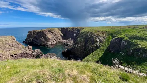 A rugged coastline with a wooden set of steps heading down towards the water