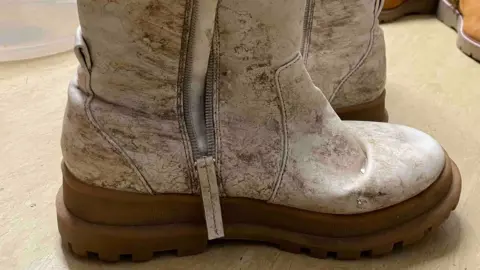 A pair of dirty and worn boots that will need to be thrown away at a cost to the Blythe House Hospice Charity