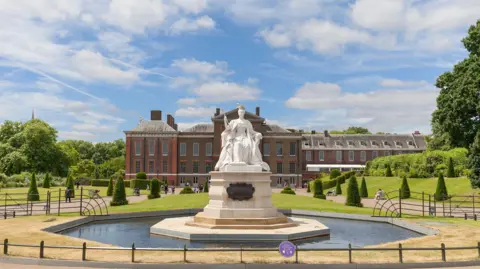 Getty Images An 18th century palace with a large marble statue on a pedestal in the middle of a pond at the front of the building. 