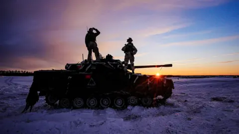 PA Media Siluetas de soldados estonios sobre un tanque durante la puesta de sol con nieve a su alrededor durante los ejercicios militares de la OTAN en el campo de tiro de Tapa en Estonia el 2 de febrero.