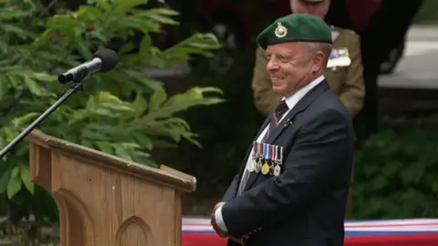 Jason Cox wearing his royal marines uniform stood behind a lectern 