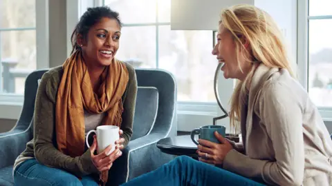 Getty Images Friends chatting in a home