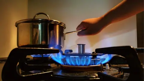 Getty Images Person holds pot over gas hob