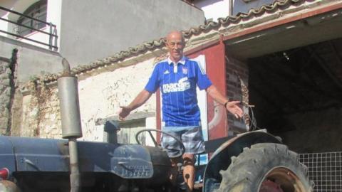 Valentine Powell wearing an Ipswich Town shirt and standing on top of a tractor