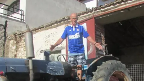 Jasmine Powell Valentine Powell wearing an Ipswich Town shirt and standing on top of a tractor