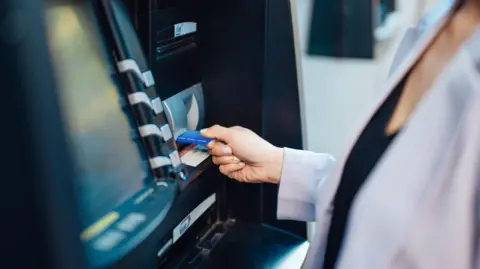 The image shows a young woman using an automatic cash machine to withdraw money, make a bank transfer and check account balances.