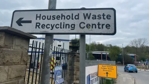 A road sign pointing to 'household waste recycling centre'