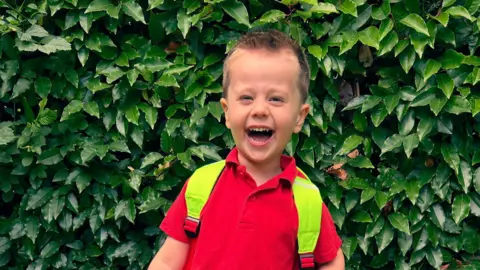 Ellie Thompson A child wearing a red polo top and a backpack with bright yellow straps.