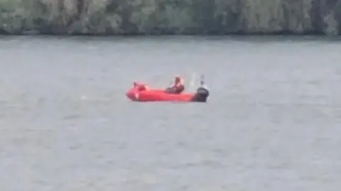 A blurry, zoomed-in image of a red rescue boat on open water. 