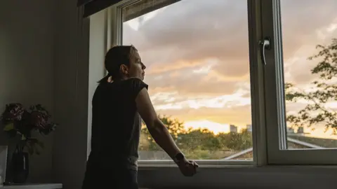 Getty Images/Justin Paget Woman at window