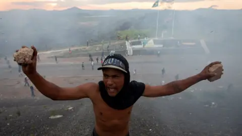 EPA Opponents of Venezuelan President Nicolas Maduro clash with members of Venezuelan police on the border between Brazil and Venezuela. Photo: 23 February 2019