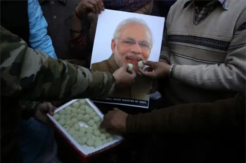 EPA Indian people feed sweets to a poster of Indian Prime Minister Narendra Modi as they celebrate the Indian Air Force"s air strike across the Line of Control (LoC) near the international border with Pakistan