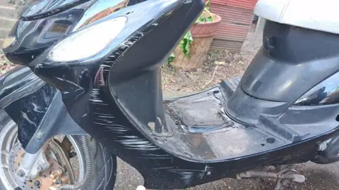 Sean Henry A moped with black paint has white scratches all down one side after a crash involving a pothole.