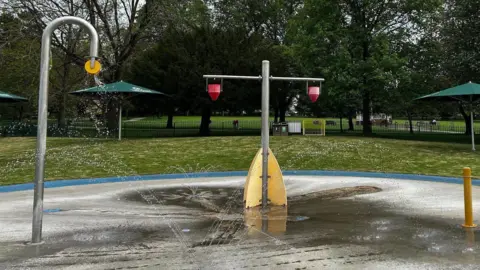 Chippenham Town Council A splash pad with green grass and trees behind it.