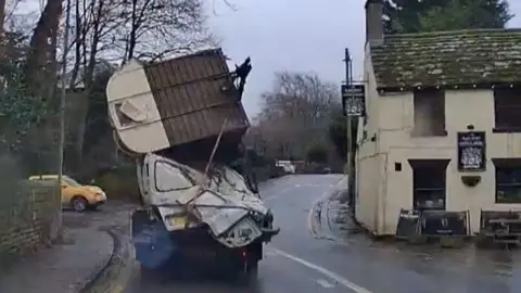 A vehicle which has crashed with a horse box on a road.
