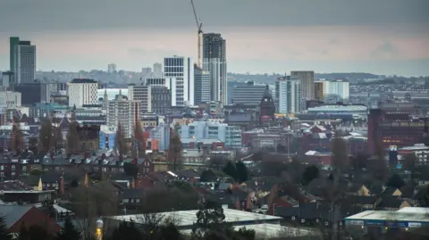 The Leeds skyline, pictured shortly before dusk. A number of skyscrapers can be seen. It's a cloudy day.