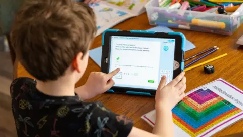 PA Media A boy learns from home with a tablet