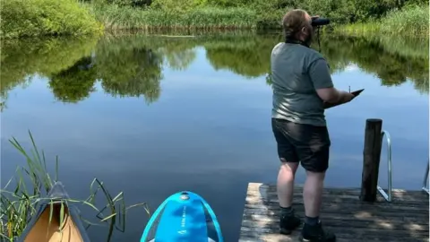 BBC Student looking through binoculars to monitor species at Elmore Court