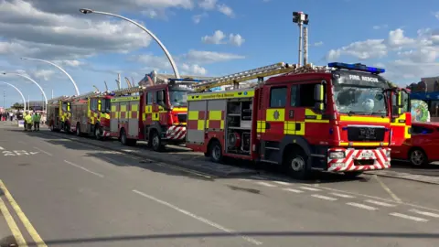 Firefighters parked on the street in front of the attraction, people in sight