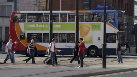 Getty Images people walk on pavement with bus behind