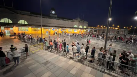 Fans queue outside Cardiff Central railway station after the show