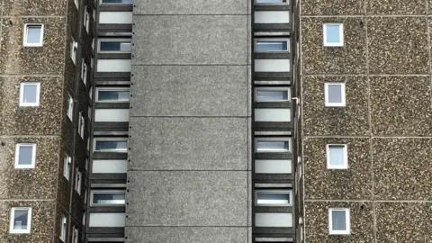 A close-up shot of a LPS block on the Ledbury estate, showing the panel structure of one of the blocks including grey concrete and pebbledash panels and white UPVC windows