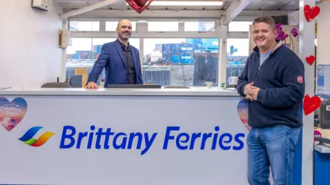 Paul Acheson of Brittany Ferries and Islands Unlimited’s Chad Murray stood together in front of a Brittany Ferries desk.
