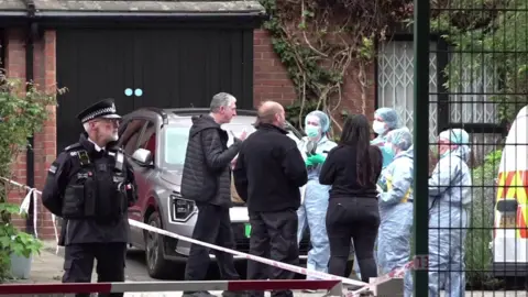 Police and forensic teams standing outside house being searched in Shepherd's Bush