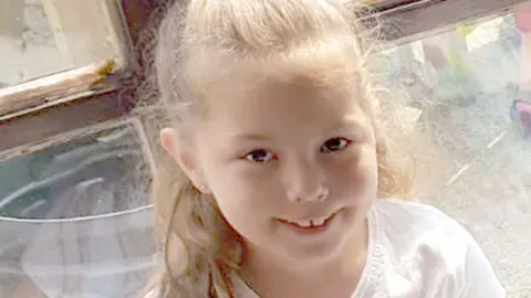 Olivia Pratt-Korbel, nine, with blonde hair tied in a pony tail, smiles for the camera. She is pictured wearing a white t-shirt.